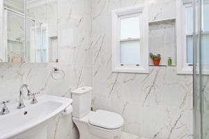 a white bathroom with a toilet and a sink at The Little Lake House in Primbee +16 photos