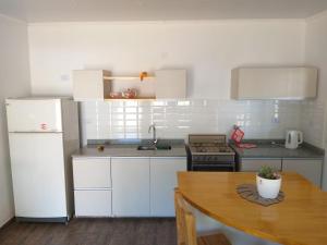 a kitchen with white appliances and a wooden table at Cabaña Los Pajaritos in Villa Rumipal