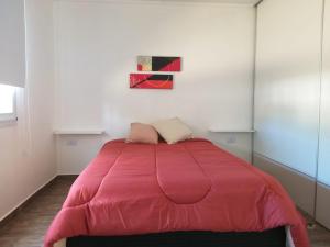 uma cama com um edredão rosa num quarto em Cabaña Los Pajaritos em Villa Rumipal