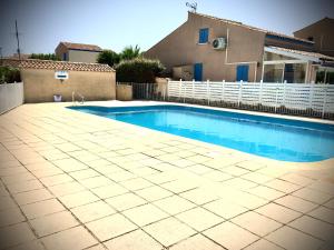 a swimming pool in front of a house at De la Clape à la mer mon petit pavillon labellisé - f2- piscine commune - wifi gratuit- parking privé - arrivee autonome - 800 m plage - grande terrasse abritée vent - in Saint Pierre La Mer