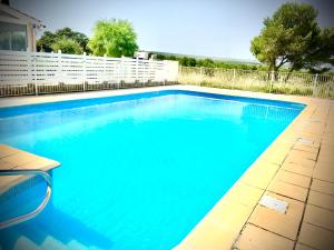 a swimming pool with blue water in a yard at De la Clape à la mer mon petit pavillon labellisé - f2- piscine commune - wifi gratuit- parking privé - arrivee autonome - 800 m plage - grande terrasse abritée vent - in Saint Pierre La Mer +8 photos