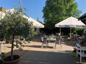 a patio with tables and chairs and umbrellas at Ilvericher Hof in Meerbusch