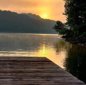 een zonsondergang boven een meer met een houten steiger bij Beautiful Lakefront Cottage with Boat Dock in Lucas