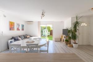 uma sala de estar branca com uma mesa e um sofá em Maison familiale avec piscine em Mauguio