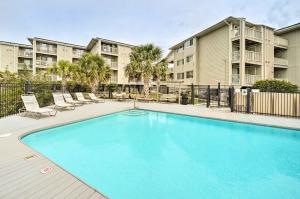 una piscina con sillas y un edificio en Coastal Condo with Pool Access - Steps to Beach en Carolina Beach