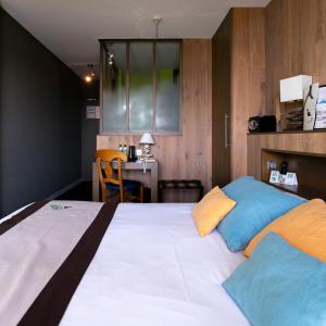 1 dormitorio con 1 cama grande con almohadas azules y naranjas en Logis Hôtel Restaurant Le Calluna en Préfailles