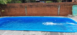 a blue swimming pool in front of a brick wall at Casa con piscina en Gobernador Roca in Gobernador Roca