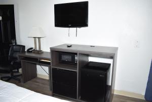 a room with a desk with a microwave and a television at Super 8 by Wyndham Fredericksburg in Fredericksburg