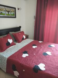 a bed with a red blanket with white flowers on it at Charmant Studio piscine mdiq CaboNégro Martil in Cabo Negro