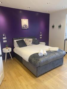 1 dormitorio con 1 cama grande y pared morada en PRIVATE•ASTONISHING•CONTRACTOR•DETACHED•LutonAirport•WI-FI•PARKING•SPACIOUSNESS, en Luton