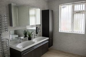 ein Bad mit einem Waschbecken, einem Spiegel und einem Fenster in der Unterkunft PRIVATE•ASTONISHING•CONTRACTOR•DETACHED•LutonAirport•WI-FI•PARKING•SPACIOUSNESS in Luton