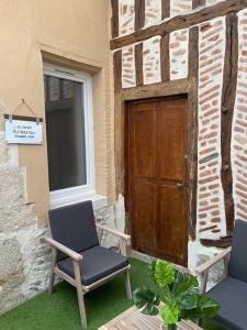 two chairs sitting outside of a building with a door at Studio Manhattan WIFI Plein de charme in Gien