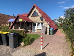 ein Haus mit einem roten Dach mit Mülltonnen in der Unterkunft Ferienhäuser Seemannsgarn in Friedrichskoog-Spitze
