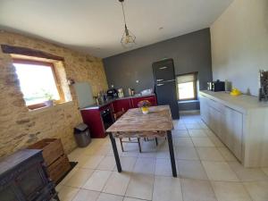 Una cocina con una mesa de madera y un refrigerador. en gîte paisible en pleine nature, en Lolme