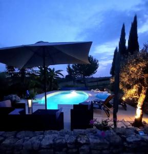 una gran piscina con sombrilla y sillas en gîte paisible en pleine nature, en Lolme 3 fotos más