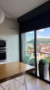 オロットにあるÁtico de diseño con terraza en el centro de Olotのキッチン(木製テーブル付)、大きな窓が備わります。