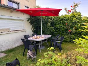 - une table et des chaises avec un parasol rouge dans la cour dans l'établissement Suite "Olga 1 ", à Verdun-sur-Meuse