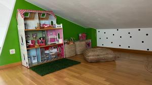 una sala giochi con una casa per bambole in una stanza con pareti verdi di Ático de diseño con terraza en el centro de Olot a Olot