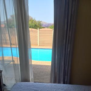 a bedroom window with a view of a swimming pool at Lime Court Four in Pretoria