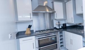 a kitchen with white cabinets and a stove top oven at Guerneville place 1 bedroom Luxury Apartment Gants-Hill in Illford in Redbridge