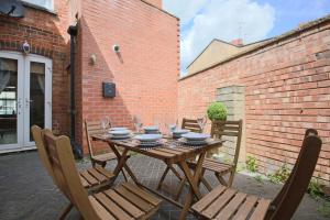 a wooden table with chairs and wine glasses on it at Spacious House in City Centre - Sleeps up to 9 - Free Parking, Super-Fast Wifi, Garden, Balcony, and Smart TV with Virgin TV and Netflix by Yoko Property in Northampton