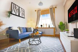 Una sala de estar con un sofá azul y una mesa. en Spacious House in City Centre - Sleeps up to 9 - Free Parking, Super-Fast Wifi, Garden, Balcony, and Smart TV with Virgin TV and Netflix by Yoko Property, en Northampton