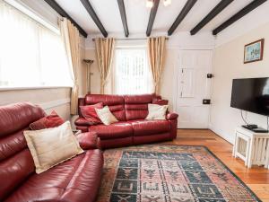 a living room with a leather couch and a television at Scotch Hall Cottage in Llangollen