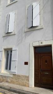 a building with two windows and a wooden door at Logis de la Foulerie in Bize-Minervois