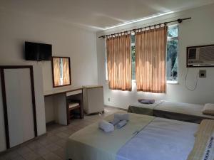 a bedroom with two beds and a desk and a television at Belamar Hotel in Mangaratiba