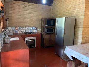 a kitchen with a stainless steel refrigerator and a table at Chico Bertolino / Reserva Alto da Colina in Conceição da Ibitipoca
