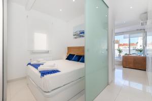 シッチェスにあるBeach penthouse Sitges Rentalsの白いベッドルーム(ベッド1台付)とガラスの壁
