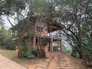 una casa de ladrillo con un árbol delante de ella en Varandas da Serra / Reserva Alto da Colina, en Conceição da Ibitipoca