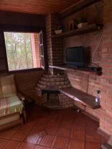 a small room with a tv in a brick wall at Varandas da Serra / Reserva Alto da Colina in Conceição da Ibitipoca