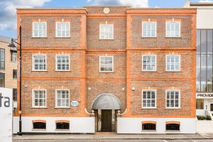 a large red brick building with a door at Charming 1 BR apt , town centre, wifi, free parking by Tent Serviced Apartments in Staines