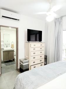 a bedroom with a bed and a dresser with a television at Ocean Palms - 1Bed 1Bth King Suite Condo in Cabarete