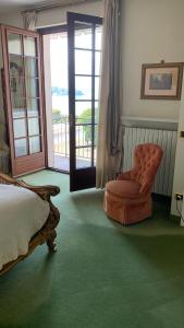 a bedroom with a bed and a chair and a window at Residenza Le Magnolie in Verbania