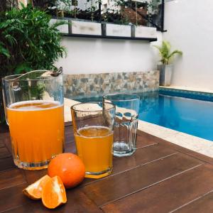tres vasos de zumo de naranja y naranjas en una mesa de madera en Edificio Itasu - 4to - alquileres temporales en Posadas