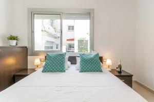 1 dormitorio con 1 cama blanca grande con almohadas azules en Fragata Sitges Rentals, en Sitges
