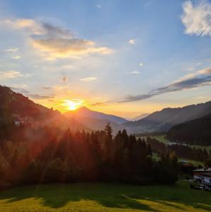 a sunset in the mountains with a green field at Ferienwohnung Zauberwinkelweg mit Traum-Aussicht! in Wildschönau