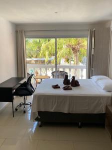 a bedroom with a bed and a desk and a window at Canoa Suites & Apartments in Canoa Quebrada