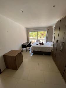 a bedroom with a bed and a desk and a window at Canoa Suites & Apartments in Canoa Quebrada