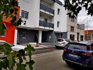 un estacionamiento con autos estacionados frente a un edificio en GOLDEN - self CHECK IN, en Osijek