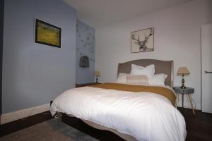 1 dormitorio con 1 cama grande con sábanas blancas en Lovely, cosy 3 bedroom apartment en Teddington