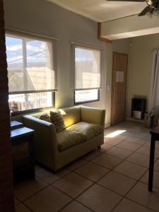 uma sala de estar com um sofá e duas janelas em La Osadia Cabañas y Suites Solo Adultos em Mina Clavero