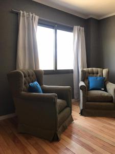 een woonkamer met 2 stoelen en een raam bij La Osadia Cabañas y Suites Solo Adultos in Mina Clavero