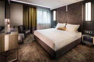 a bedroom with a large bed and a desk and a chair at -- ESTE PARK HOTEL -- part of Urban Chic Luxury Design Hotels - Parking & Compliments - next to Shopping & Dining Mall Plovdiv in Plovdiv