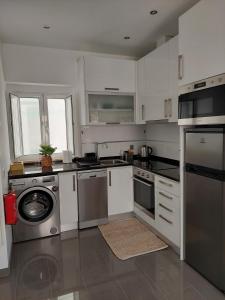 eine Küche mit weißen Schränken und Küchengeräten aus Edelstahl in der Unterkunft SEA AIR Alojamento Local in Nazaré