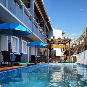 a swimming pool with chairs and umbrellas next to a building at Pousada Manacá in Piraju