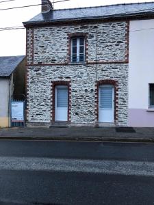 a brick building with three windows on a street at Joli studio cosy in Châteaubriant
