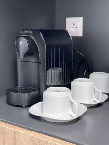 una cafetera y dos tazas en un mostrador en Smart Apartment l, en Huncovce